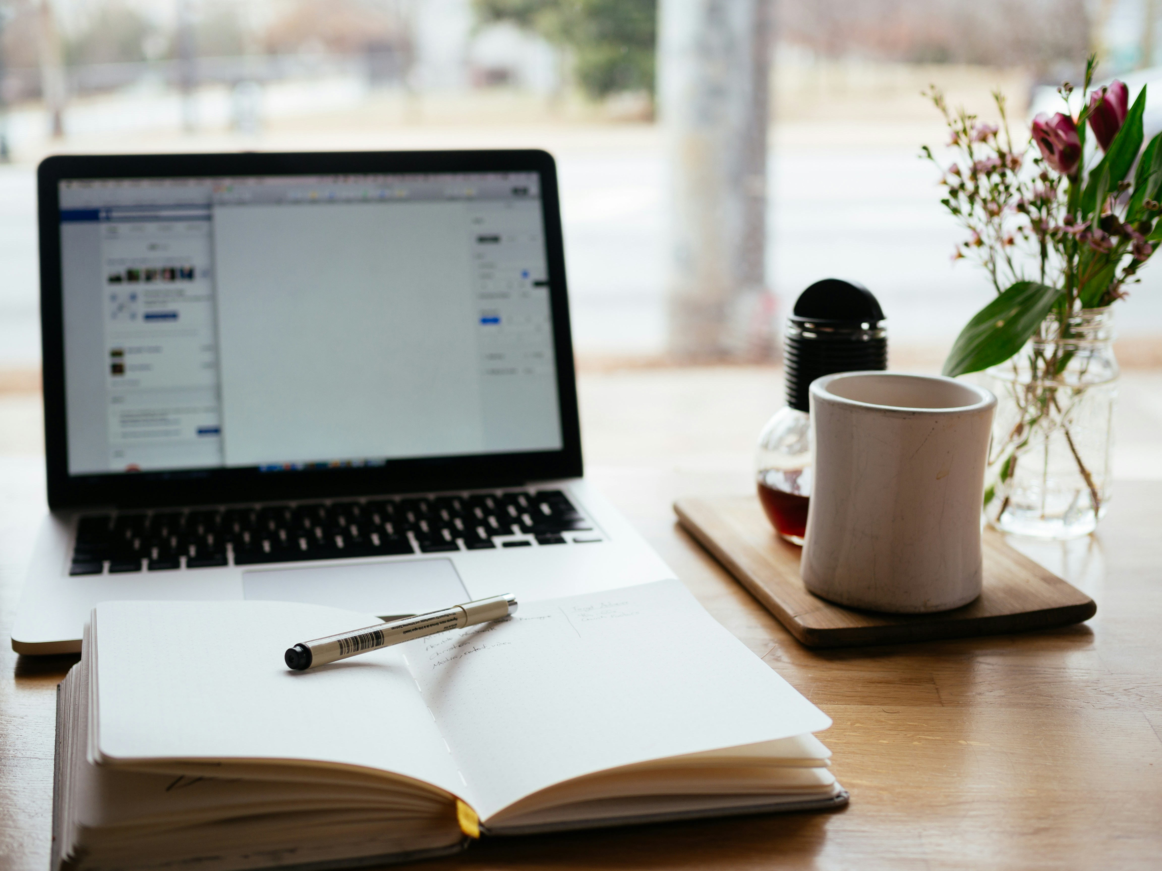 Schreibtisch mit Laptop und aufgeklappten Notizbuch Schreibtisch mit Laptop und aufgeklappten Notizbuch